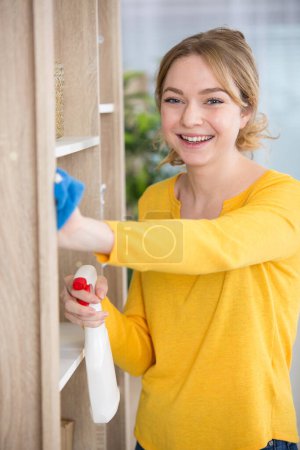 woman dusting the home with a smile