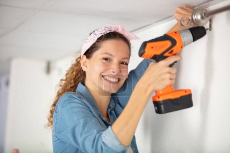 happy girl using a drill in a wall