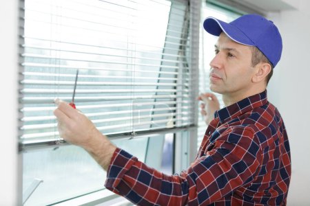 man is installing window blinds