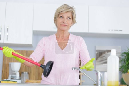 frustrated mature woman holding a sink plunger