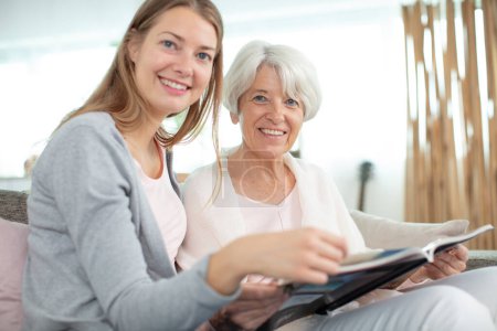 elderly woman and daughter checking album at home