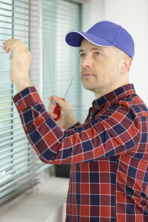 male contractor installing window blinds