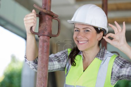 female builder by acrow prop making ok gesture