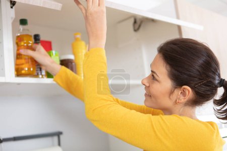 adult woman picking food from storage cabinet in kitchen