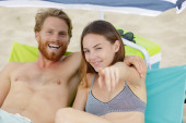 young couple on the beach pointing forwards Stickers #658432648