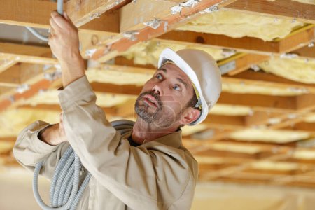 Professioneller Bauunternehmer verlegt neue Kabel ins Dach