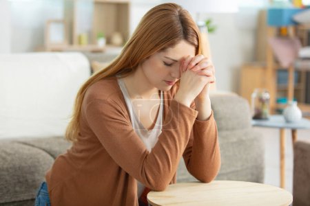 Frau kniet im Wohnzimmer im Gebet