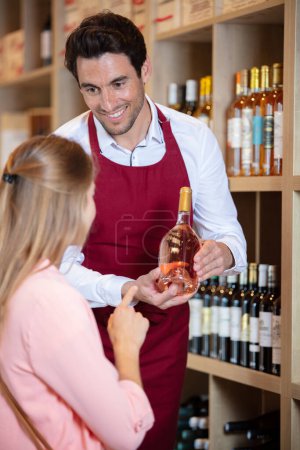 wine seller showing bottle of wine to female customer