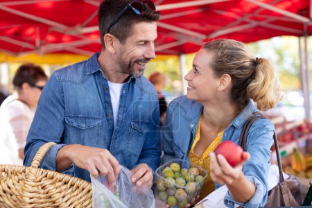 pareja joven comprando frutas y verduras en un mercado
