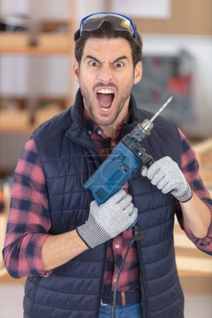 man holding drill and making a crazy expression