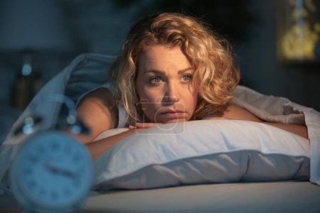 mujer deprimida acostada despierta por la noche