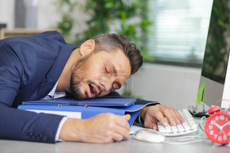 Homme d'affaires endormi sur une pile de dossiers
