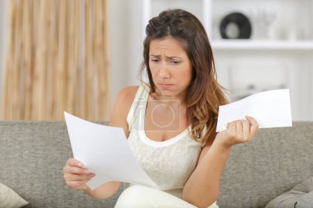 sad woman reading a letter at home