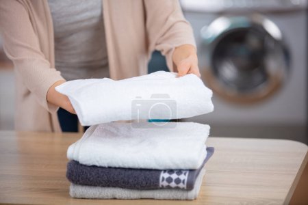 photo recadrée de femme empilant des serviettes propres