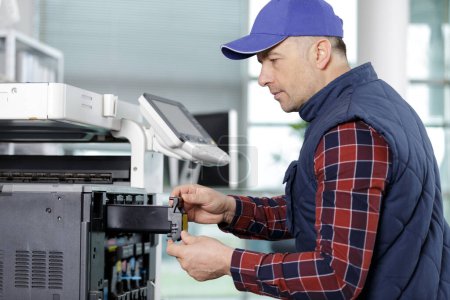 hombre técnico reparación de una impresora en el lugar de negocios en el trabajo