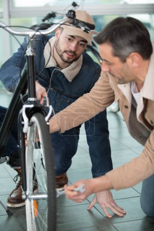 dos hombres bombeando los neumáticos en una bicicleta