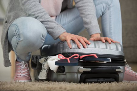 cropped view of woman cramming closed her suitcase