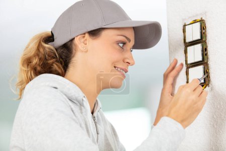 woman installing electrical switches checking the fastening of the screws