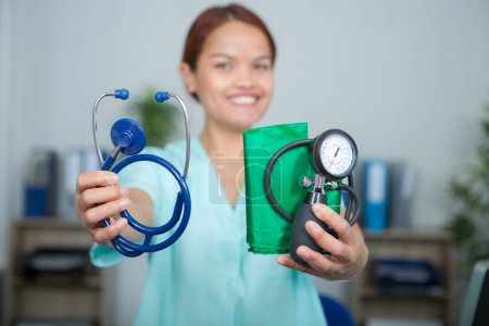 female medical worker holding stethoscope and blood pressure equipment