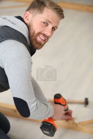 man drilling a wood frame
