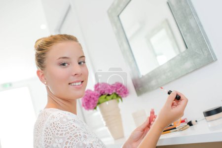 Lady applying make up in front of mirror