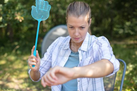 mujer en vacaciones de camping trata de atrapar un mosquito