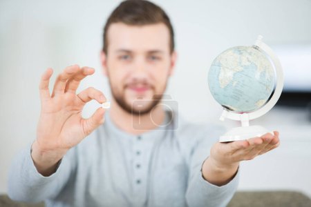 man holding a globe and a pill