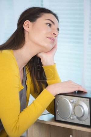 woman listening to radio at home looking thru windows