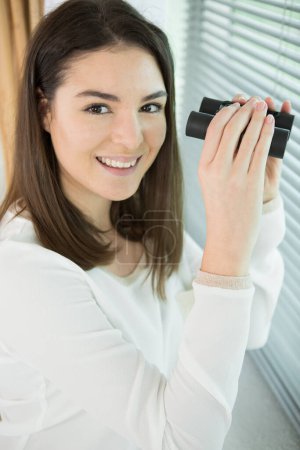 happy woman looking through binoculars at camera