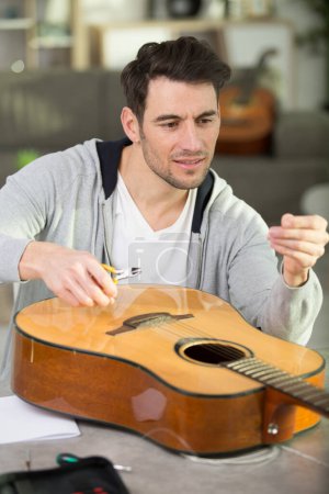bel homme réparant guitare à l'atelier