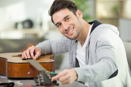 un homme heureux répare une guitare