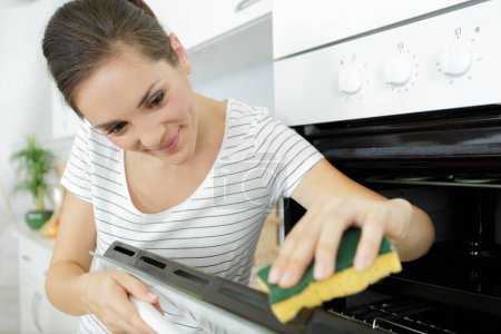 une femme nettoyant le four domestique