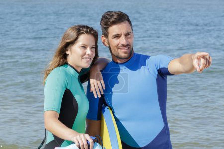 young couple of bodyboard surfers pointing at a wave