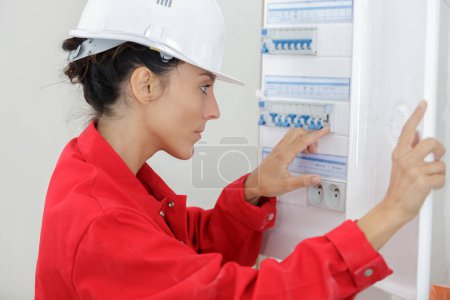 female electrician checking fuse box