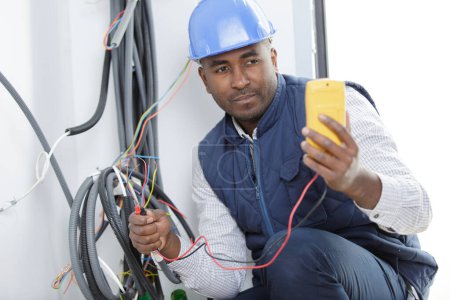 male electrician checking wiring with a multimeter