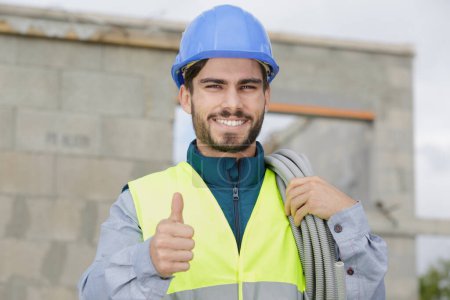 smiling handyman wearing safety helmet and showing thumb up