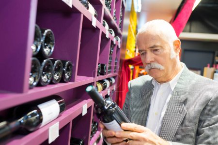 senior man choosing a wine bottle at the supermarket