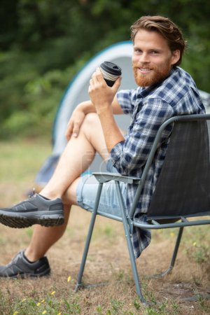 Mann trinkt morgens im Freien warmen Tee oder Kaffee