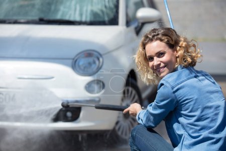woman using power washer to clean her car