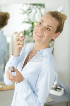 smartly dressed woman spraying perfume on her neck