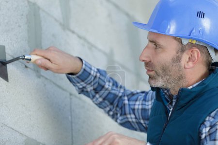 Bauarbeiter verputzt Fassade eines Hochhauses mit Spachtelmesser