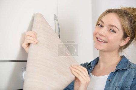 Frau hält Furnierrolle in der Hand, um ihre Küchenschränke aufzupolieren