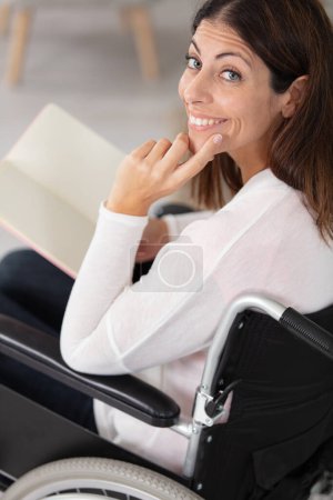 Lächelnde junge Frau im Rollstuhl blickt in die Kamera