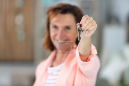 Frau mittleren Alters hält Schlüssel für neue Wohnung