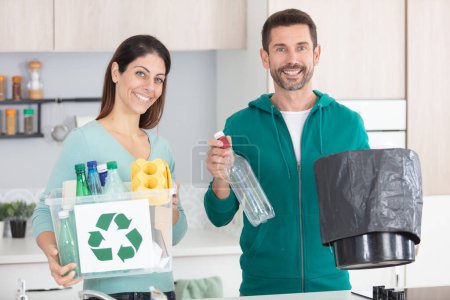 heureux couple recyclage plastique dans leur cuisine