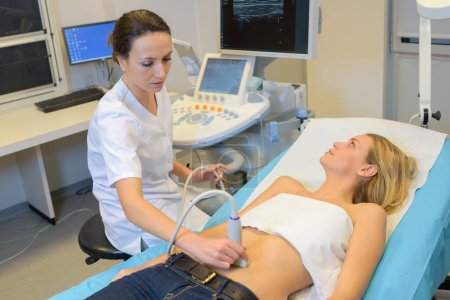 doctor moving ultrasound probe on womans stomach