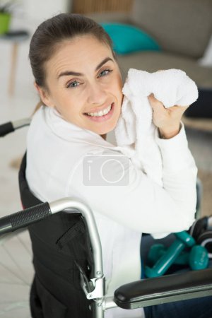 woman in wheelchair towelling off after workout with weights
