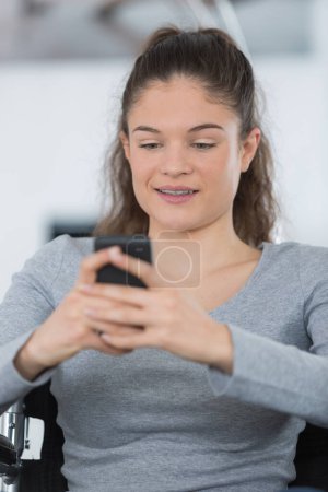 young woman on the wheelchair using a smartphone