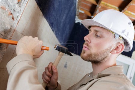 constructor golpeando una pared con un martillo
