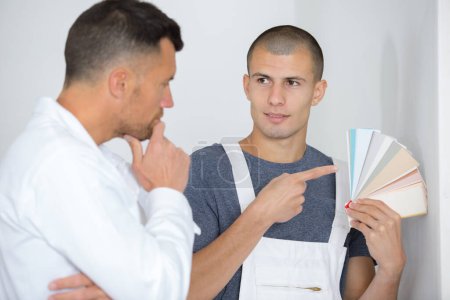 man holding a color swatch and talking to colleague